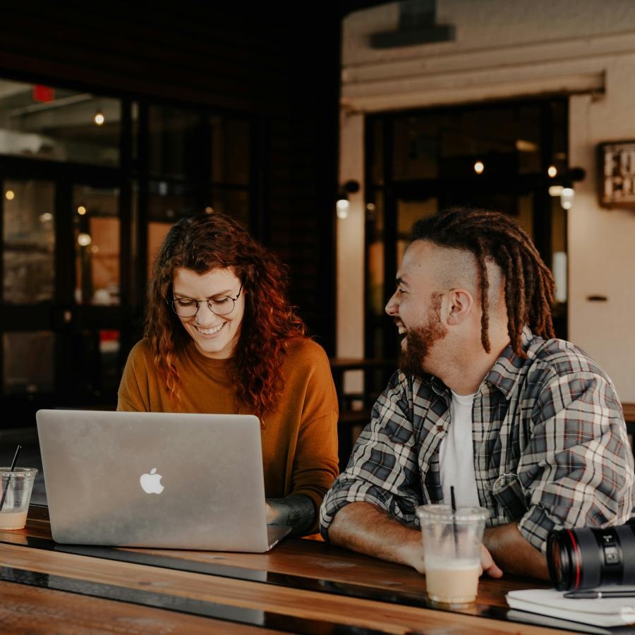 a man and woman sitting at a table looking at a laptop