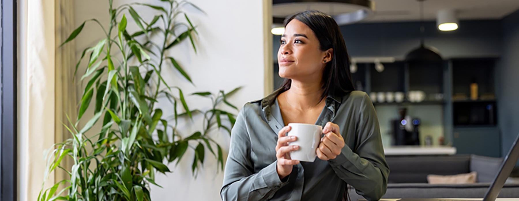 a person sitting at a table with a laptop holding a cup of tea